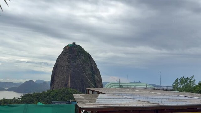 P&atilde;o de A&ccedil;&uacute;car Sugarloaf Mountain in Rio de Janeiro Brazil with Bondinho cable car lines ascending granite peak within Guanabara Bay coastal landscape, lateral pan shot
