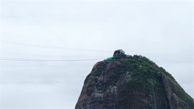 Sugarloaf Mountain cable car station on P&atilde;o de A&ccedil;&uacute;car in Rio de Janeiro Brazil with granite peak and suspended cable lines forming part of the Bondinho system, drone telephoto static shot