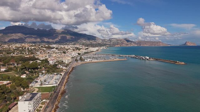 Albir and Altea Costa Blanca Spain.Rising drone footage of seafront,harbour and marina from with calm blue water,views across to Benidorm,the mountains and clouds in bright sun