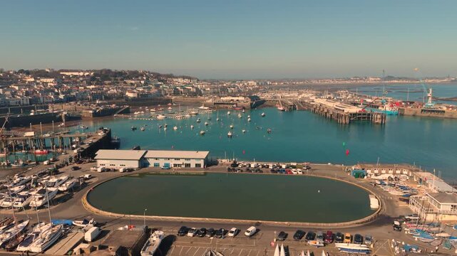St Peter Port Guernsey.Reveal of model yacht pond overlooking harbour in golden hour with clear blue sky and views over the entire harbour and beyond