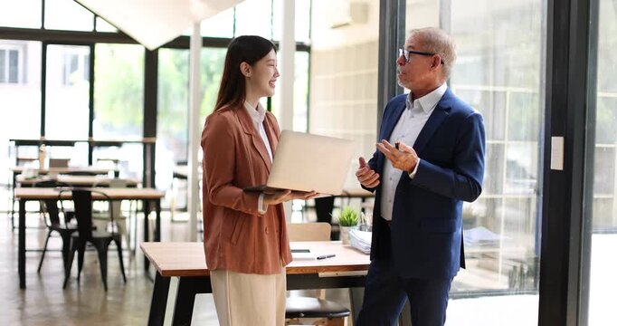 Two business people partners coworkers colleagues discussing about work at office stairs. Female workers manager showing document contract graphs and charts for her mature senior boss