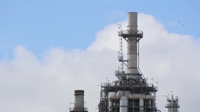 Old Oil Refinery Stack With Clouds And Birds