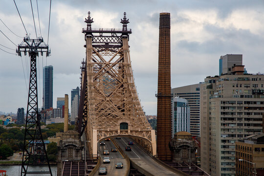 Aerial view of the Ed Koch Queensboro Bridge with cars driving across the cantilever structure and the Roosevelt Island Tramway tower New York, New York, United States.