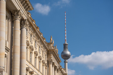 The Berlin TV Tower rises behind ornate historic buildings under a blue sky. The iconic landmark dominates the skyline of the German capital. © Jakob