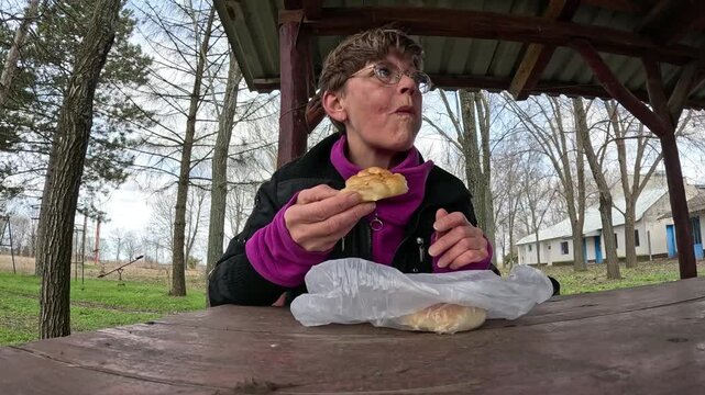 Adult woman in glasses eating delicious balkan burek in outdoor gazebo in early spring park