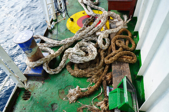 Thick nautical ropes piled on a ship deck with textured details.