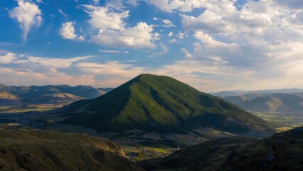 Fototapeta premium Rolling green hill rises against blue sky