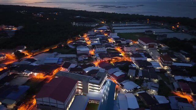 Nighttime aerial footage of Sungai Udang village with street lights, buildings, nearby coastal ponds.
