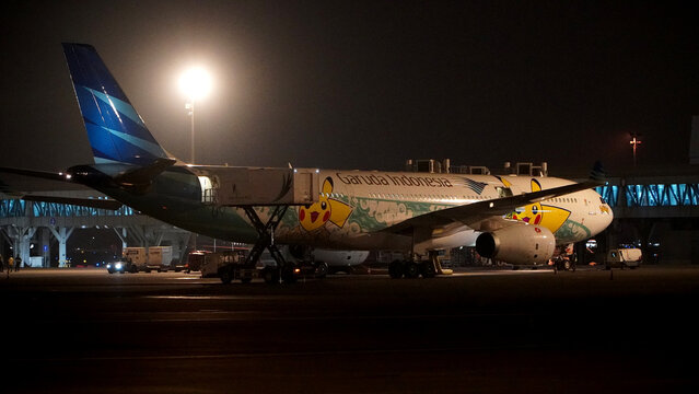 Commercial airplane Garuda Indonesia with unique Pikachu livery parked at the airport apron under night lights on April 22, 2026 in Soekarno-Hatta Interational Airport, Jakarta, Indonesia.