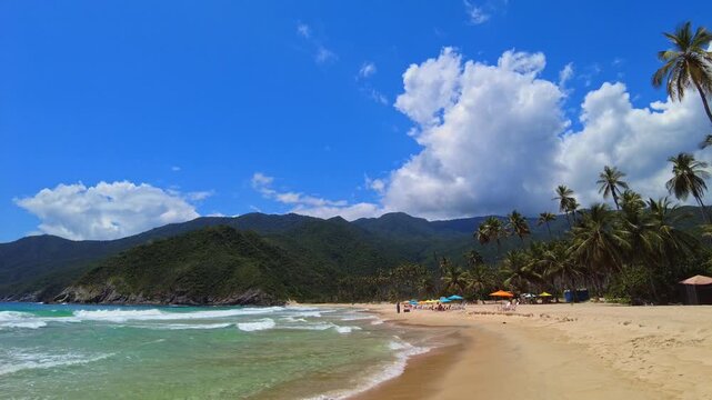 A handheld panoramic view of Playa Grande in the tourist town of Choroni, Aragua, Venezuela, with few people on a sunny day