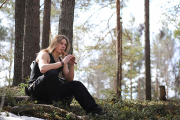 Obraz premium A musician with a tool in nature. A man is playing a flute in a pine forest. The music of the druids in the spring forest.