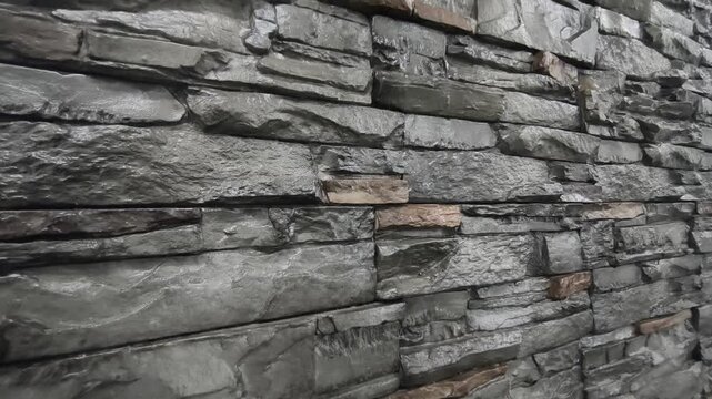 Modern artificial slate stone panels are professionally installed on an interior wall. This textured grey surface adds a sophisticated and rugged aesthetic to the room.