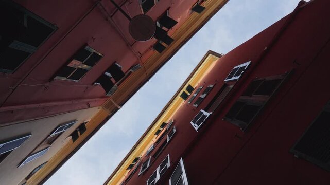 Spinning low angle view of narrow buildings and sky in Genoa