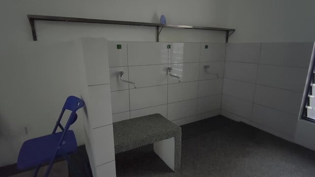 A close-up of a clean ablution area at a small Malaysian highway prayer room. Water flows for ritual washing as travelers prepare for prayer.