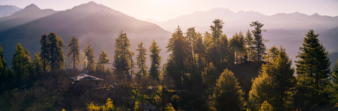 Panoramic Morning Sunrise with Sunbeams over Sainj Valley, Himachal Pradesh Himalayas. the image features dramatic sunbeams and light rays breaking over the Himalayan ridges, illuminating snow-peaks.