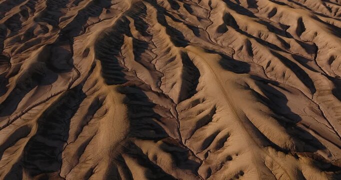 Close aerial of intricate erosion ridges forming abstract desert patterns in Utah badlands, aerial textured shadow and light backdrop