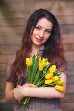 Girl with a bouquet of yellow tulips. Girl with a gift of flowers in a vase. A gift for girls on a female holiday with yellow tulips on the floor.