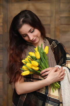 Girl with a bouquet of yellow tulips. Girl with a gift of flowers in a vase. A gift for girls on a female holiday with yellow tulips on the floor.