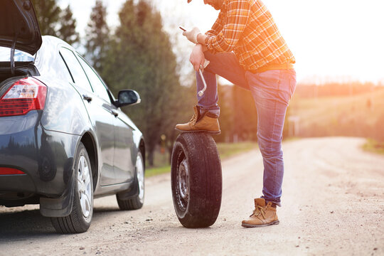 Man is sitting on the road by the car