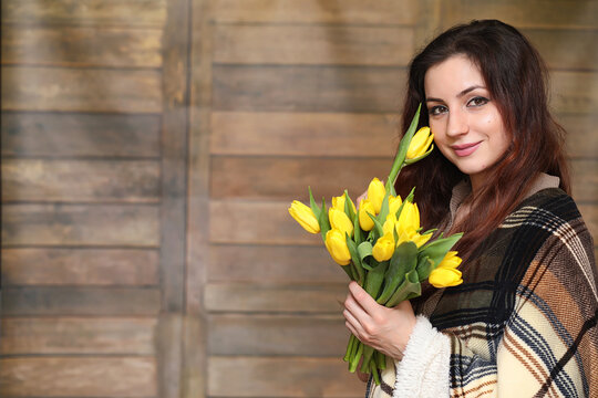 Girl with a bouquet of yellow tulips. Girl with a gift of flowers in a vase. A gift for girls on a female holiday with yellow tulips on the floor.