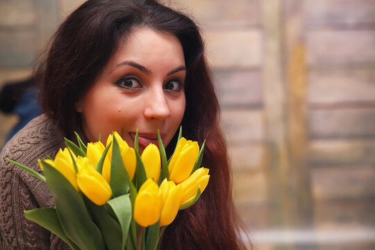 Girl with a bouquet of yellow tulips. Girl with a gift of flowers in a vase. A gift for girls on a female holiday with yellow tulips on the floor.
