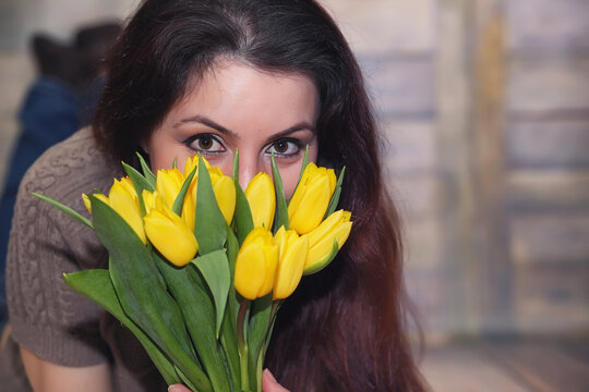 Girl with a bouquet of yellow tulips. Girl with a gift of flowers in a vase. A gift for girls on a female holiday with yellow tulips on the floor.