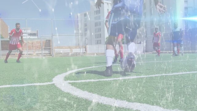 Blue player dribbling center, evading sliding tackle, keeping ball with light overlaying, sports