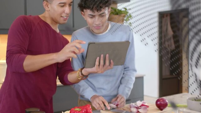 Two men grabbing tablet while prepping vegetables, following cooking recipe, dotted overlay passing