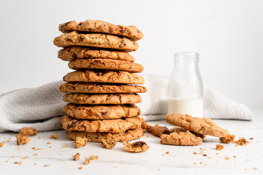Stack of homemade chocolate chip cookies next to a vintage glass