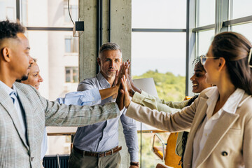 Obraz premium Group of professionals sharing joyful high five moment in office