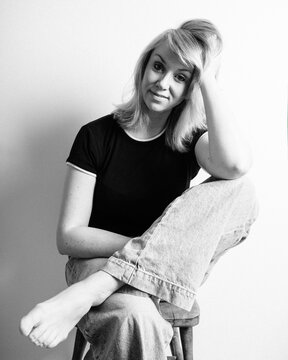 black and white portrait of a woman sat in a studio smiling