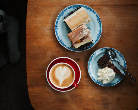 cafe latte with cake and sandwiches on a table in a cafe