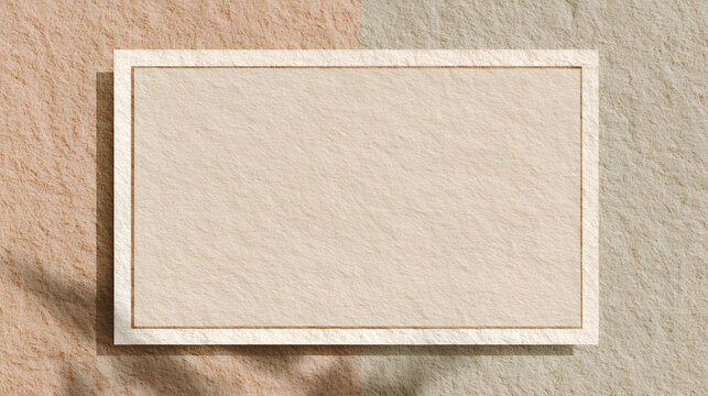 Blank beige paper frame with texture overlay, casting natural shadow on a two tone rough background, offering minimalist design space