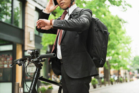 自転車通勤中にスマートフォンを確認するビジネスマン