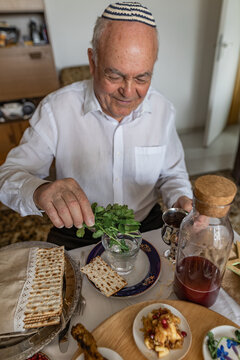 Senior man dipping parsley in salt water at Passover seder