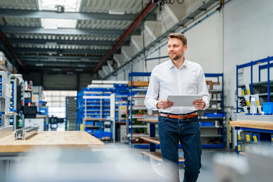 Smiling manager holding a tablet in a production hall
