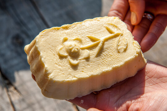 Hands holding handmade alpine butter with flower pattern
