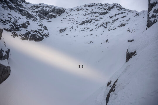 Alpinist trekking through a vast snow covered mountain valley