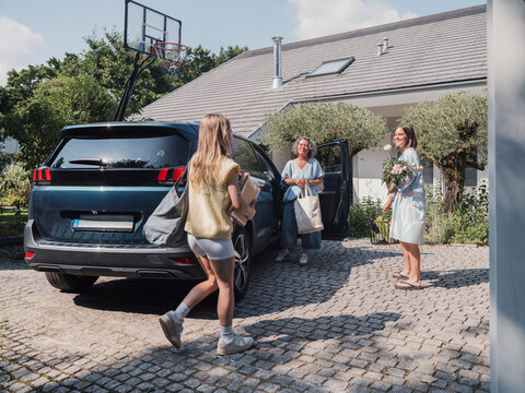 Mother and daughters arriving happily and meeting outdoors at home