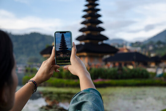 Traveler taking photo of temple in Bali Indonesia with smartphone outdoors