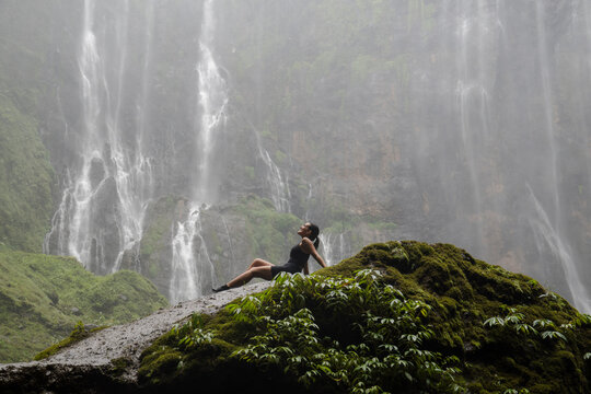 Woman relaxing at Tumpak Sewu Waterfall in Indonesian jungle