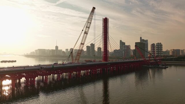 Aerial view of bridge sections being dismantled with a large crane over a river
