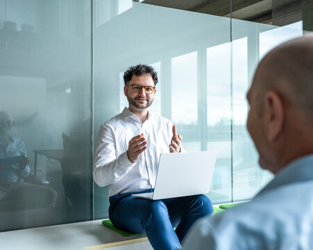 Colleagues discussing a project with a laptop in a modern office