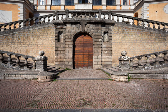 Historic wooden door at the base of a stone staircase at Villa Farnese in Caprarola, Italy. Classic Renaissance architecture with symmetrical balustrades.