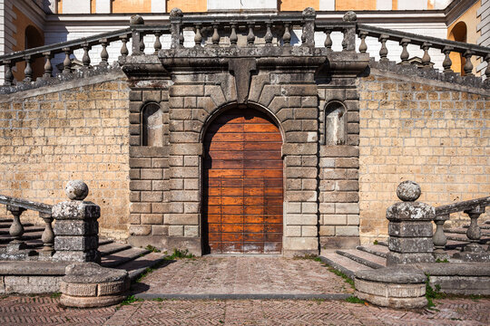 Historic wooden door at the base of a stone staircase at Villa Farnese in Caprarola, Italy. Classic Renaissance architecture with symmetrical balustrades.