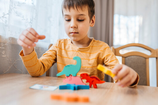 Focused child stacking colorful wooden dinosaur toys at home