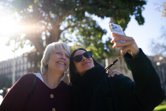 Happy friends capturing a moment with a selfie using a smartphone on a bright day in the park.