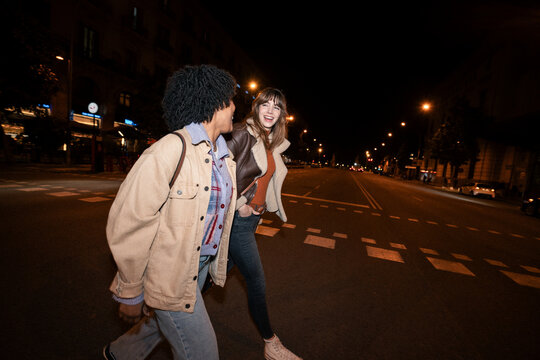 Friends walking across a city street at night