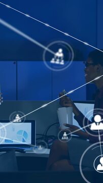 Vertical video: Woman eating box at business desk, net icons linking charts to them as man joining