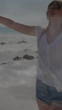 Vertical video: Woman feeling sea breeze turning opening arms smiling walking beach for travel ad